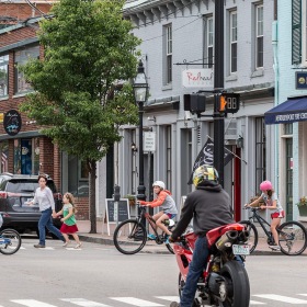 lifestyle image of people walking and riding bicycles across a retail-filled street